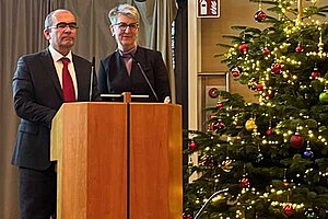 Dr. Karsten Braun und Dr. Doris Reinhardt stehen bei der Vertreterversammlung der KVBW im Dezember 2023 am Rednerpult vor einem Weihnachsbaum.